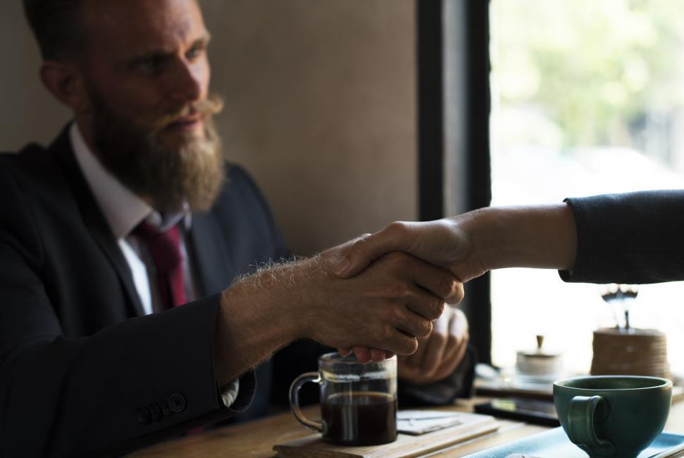 Free Image of Businessman and Businesswoman Shaking Hands at Table 