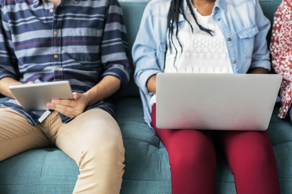 Free Image of Three People Sitting on a Couch Looking at a Laptop 