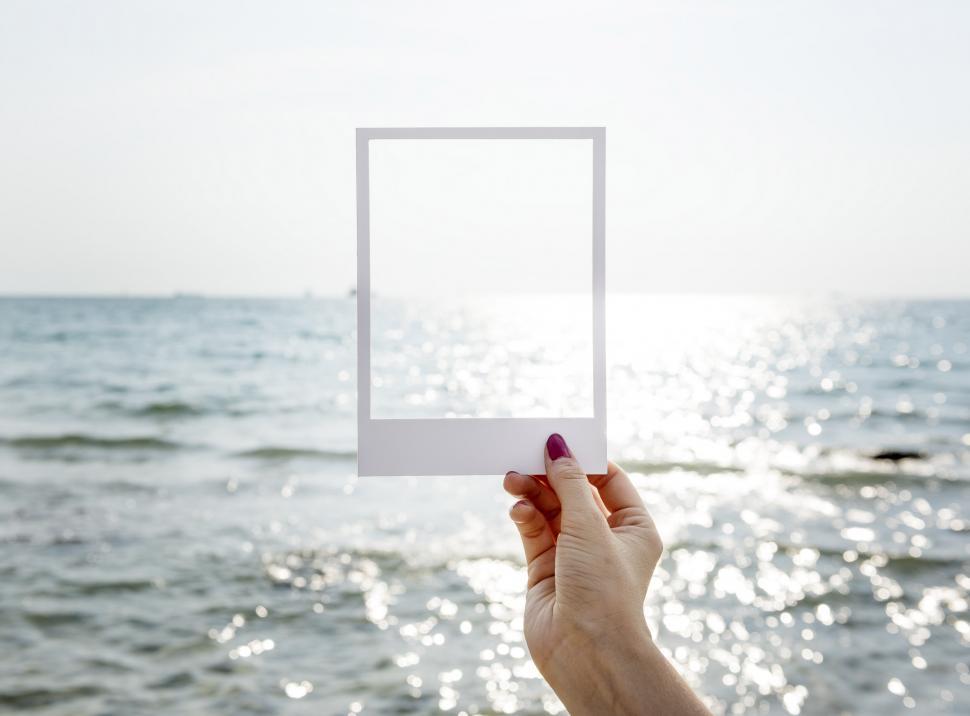 Free Image of Person Holding White Square Object in Front of Body of Water 