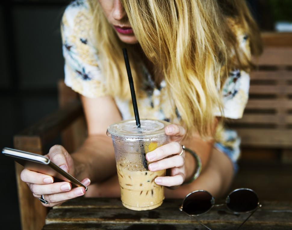 Free Image of Woman Sitting at Table With Drink and Cell Phone 