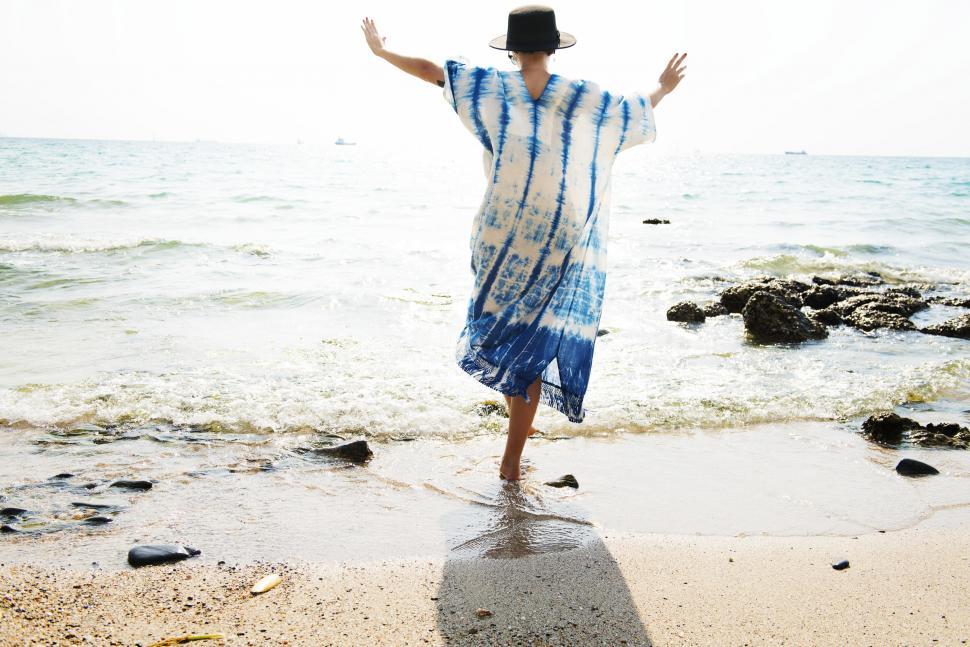 Free Image of Woman in Blue and White Dress Standing on Beach 