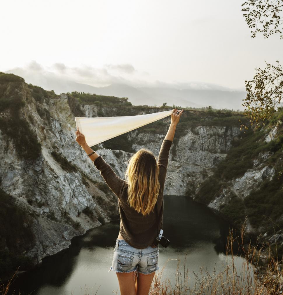 Free Image of Woman Standing on Mountain Holding White Kite 