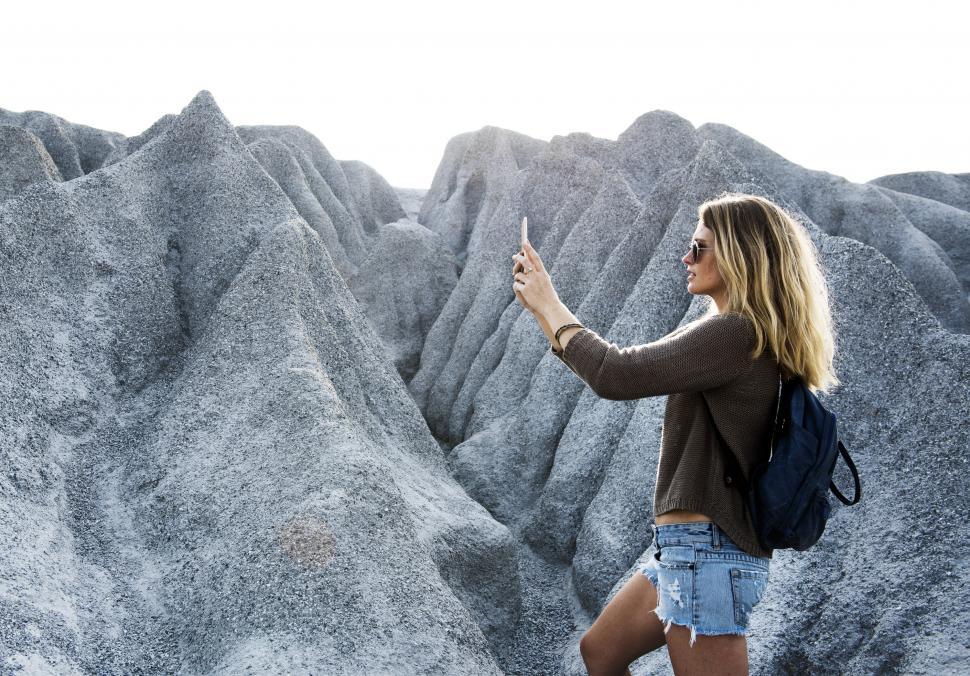 Free Image of Woman Taking Picture of Rock Formation 