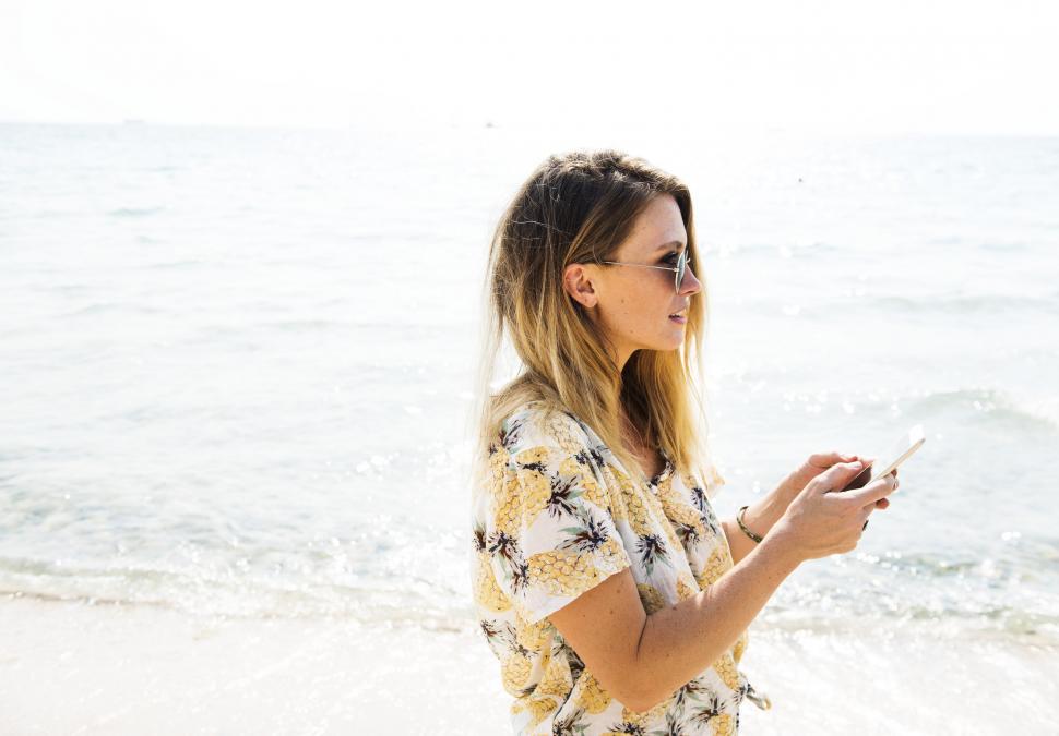 Free Image of Girl on the Beach using Mobile phone 