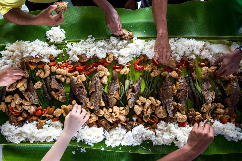 Free Image of Group of People Standing Around Large Platter of Food 