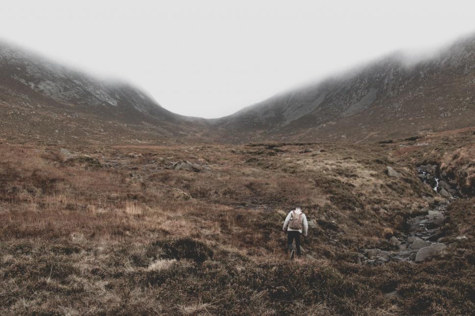 Free Image of Person Walking Through Field With Mountains in Background 