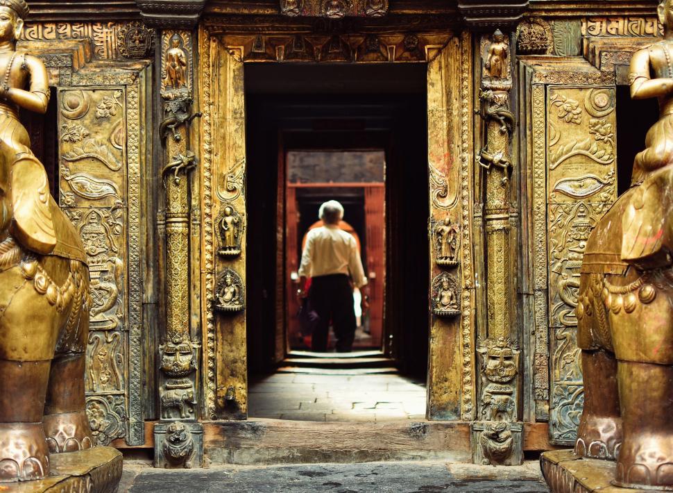 Free Image of Man Standing in Doorway Between Two Statues 