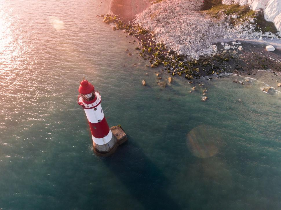 Free Image of Red and White Lighthouse in the Middle of a Body of Water 