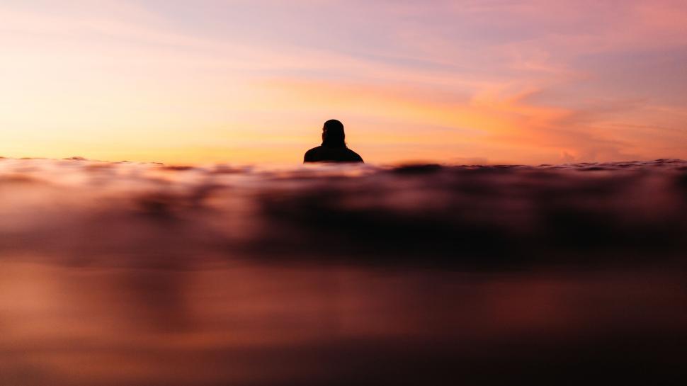 Free Image of Person Surfing in Water at Sunset With Surfboard 