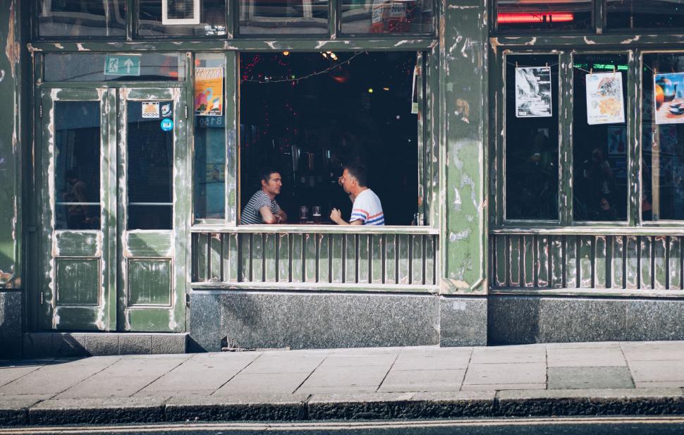 Free Image of Two Men Sitting at a Window of a Building 