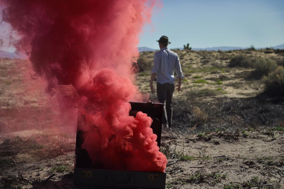 Free Image of Man Standing Next to Box With Red Smoke 