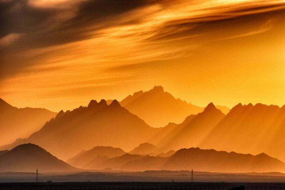 Free Image of Sunset Casting Warm Glow Over Mountain Range 