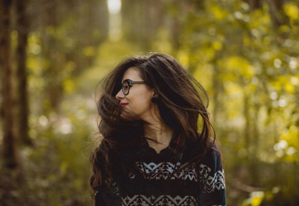 Free Image of Woman With Long Hair and Glasses Standing in the Woods 