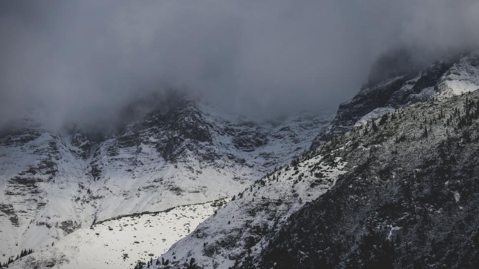 Free Image of Snow-Covered Mountain Shrouded in Clouds Under Cloudy Sky 