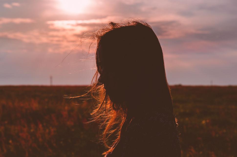 Free Image of Woman Standing in Field With Sun Behind Her 