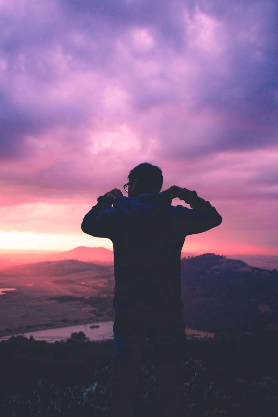 Free Image of Man Standing on Top of Hill Under Purple Sky 