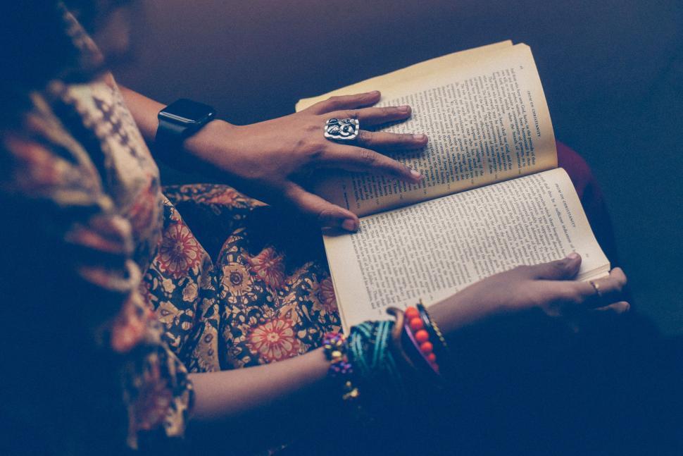 Free Image of Woman Reading Book and Holding Ring 
