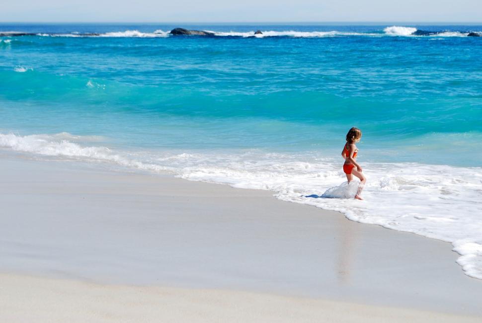 Free Image of Little Girl in Red Bikini Running Into the Ocean 