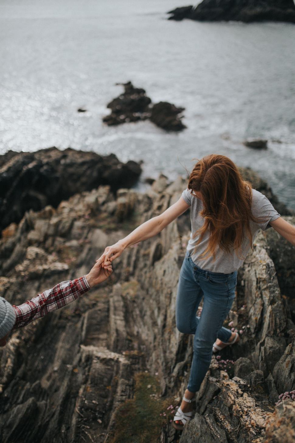 Free Image of Two People Holding Hands on a Rocky Cliff 