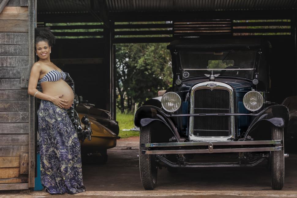 Free Image of Pregnant Woman Standing Next to Old Car 