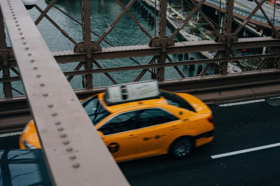 Free Image of Yellow Car Driving Across Bridge Over Water 