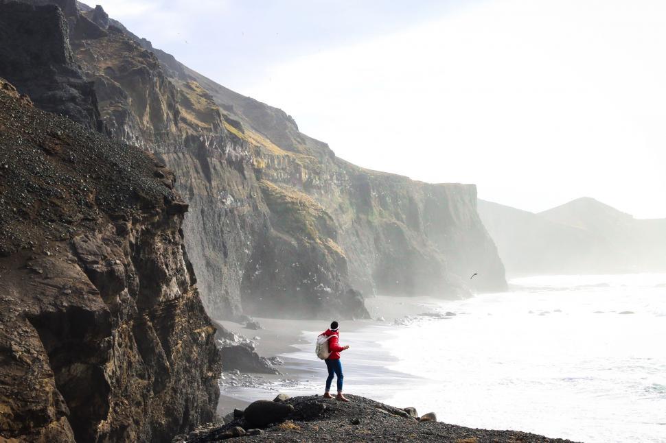 Free Image of Man Standing on Rocky Cliff Next to Ocean 