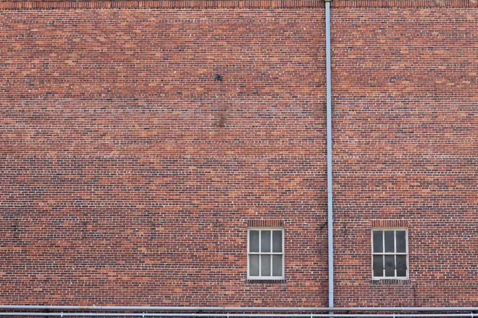 Free Image of Red Brick Building With Two Windows and a Street Sign 