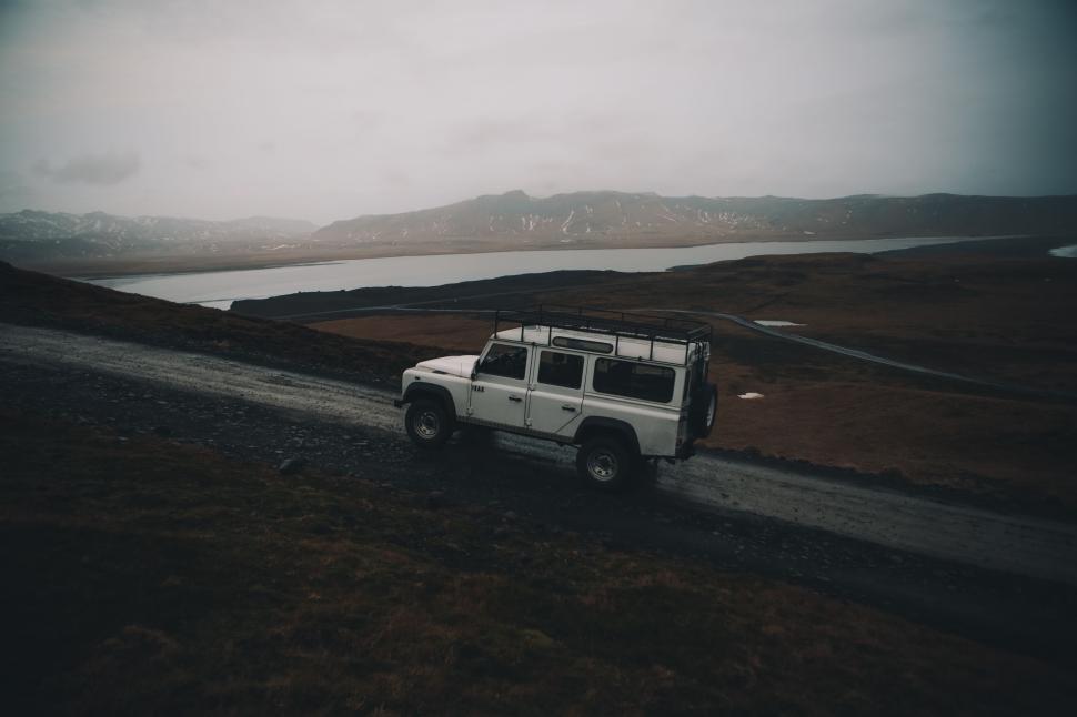Free Image of White Jeep Driving Along Waterfront Road 