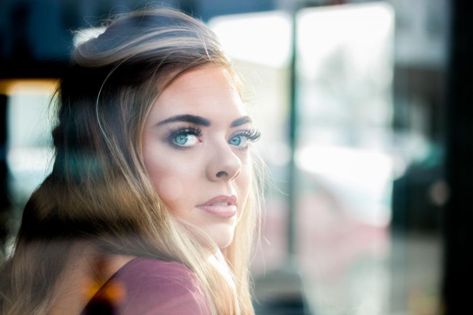 Free Image of Woman With Blue Eyes Looking Out a Window 