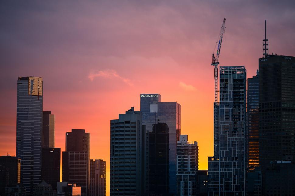 Free Image of City Skyline at Sunset With Crane in Background 