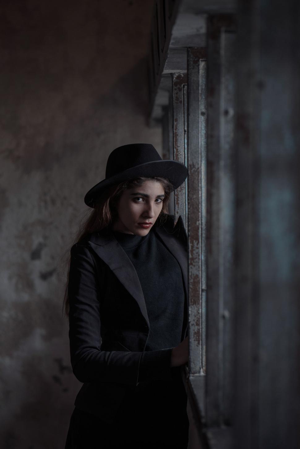 Free Image of Woman in Hat and Coat Leaning Against Wall 