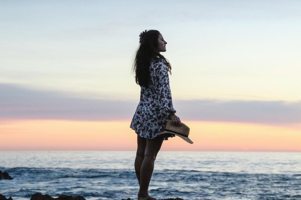 Free Image of Woman Standing on Top of Rock Near Ocean 