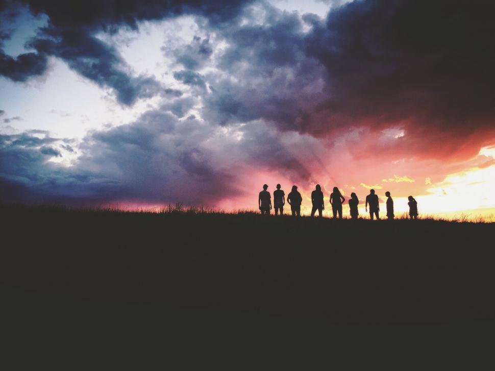 Free Image of Group of People Standing on Hill Under Cloudy Sky 