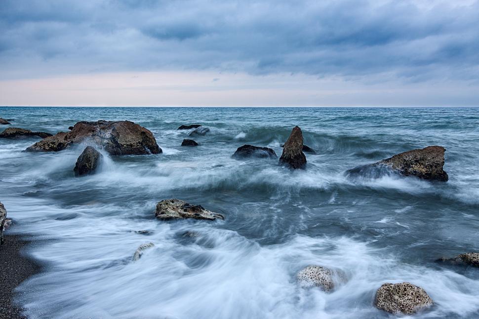 Free Image of Waterbody Surrounded by Rocks Under Cloudy Sky 