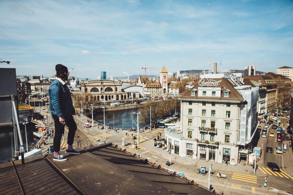 Free Image of Man Standing on Roof Next to River 