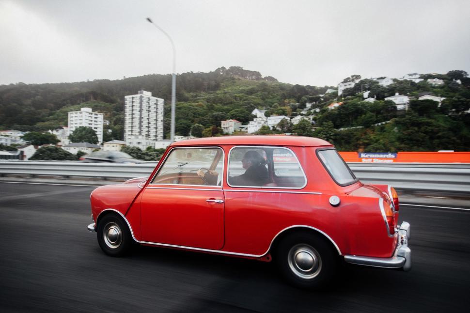 Free Image of Small Red Car Driving Down Street 
