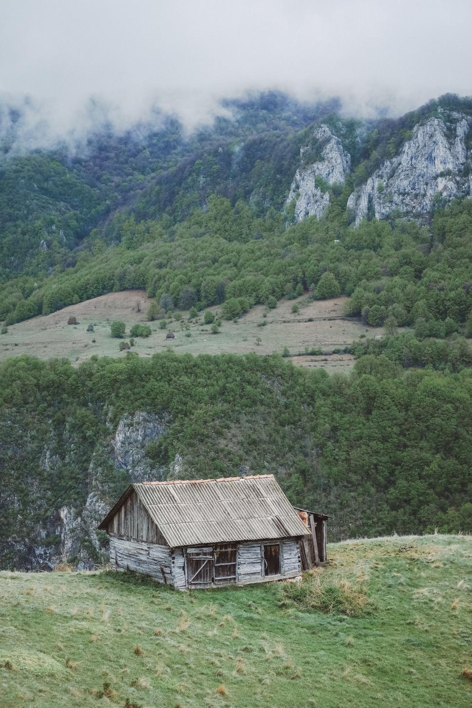 Free Image of Old Cabin in Field With Mountains 