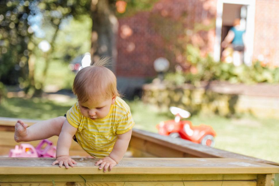 Free Image of Baby Crawling Over Wooden Table in Yellow Shirt 
