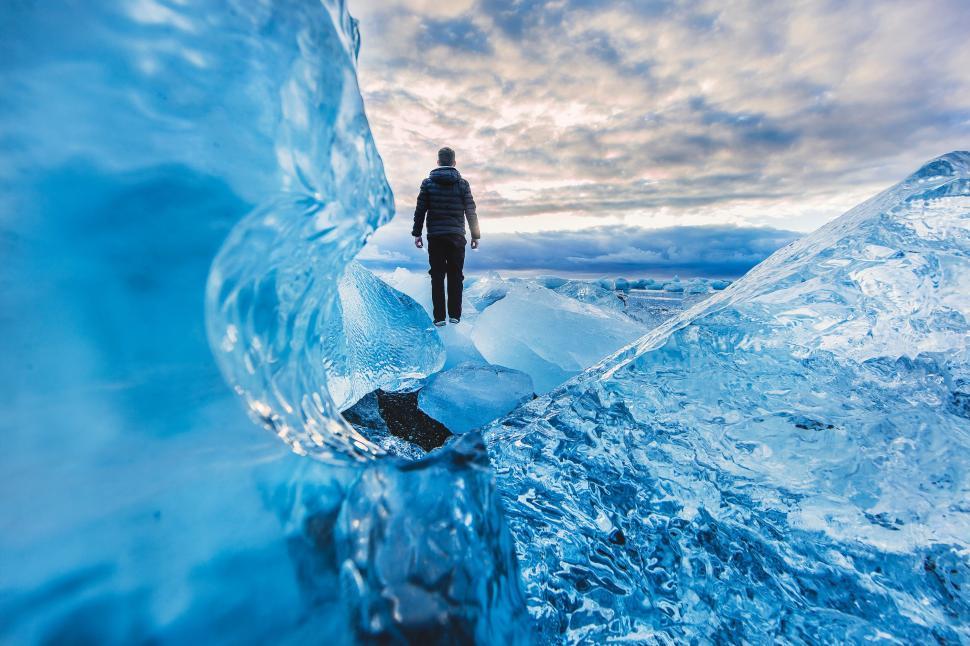 Free Image of Man Standing in Ice Cave Looking at Sky 