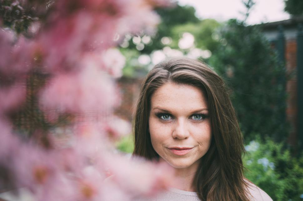 Free Image of Woman With Blue Eyes Standing in Front of Flowers 
