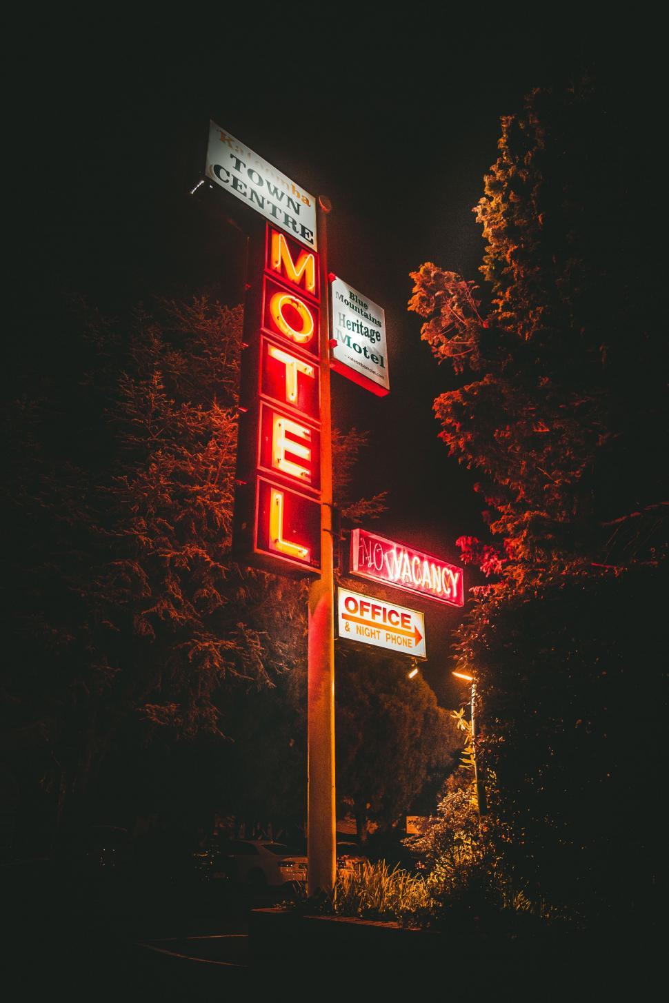 Free Image of Motel Sign Illuminated at Night With Trees in Background 