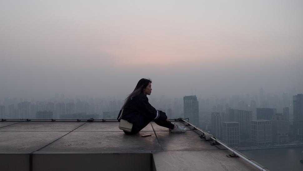 Free Image of Woman Sitting on Top of Roof in Rain 