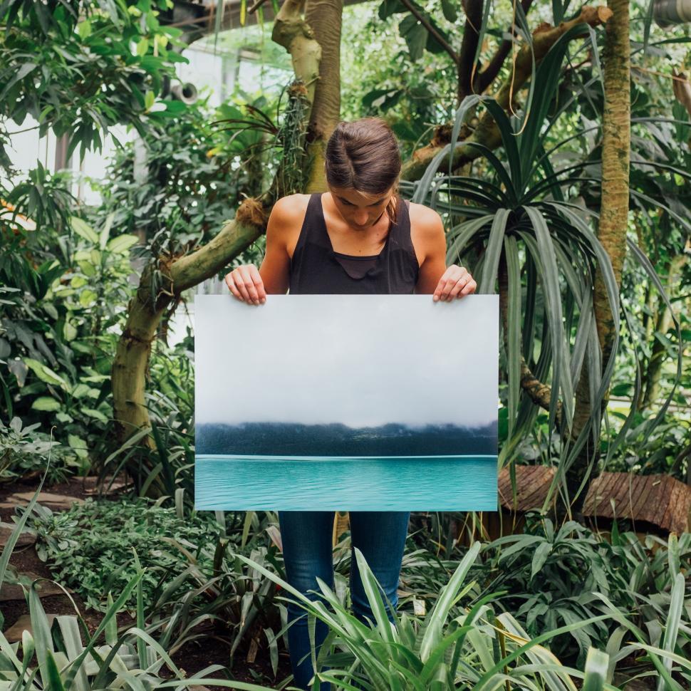 Free Image of Woman Holding Painting in Tropical Setting 