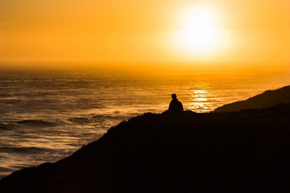 Free Image of Person Sitting on Hill Near Ocean 