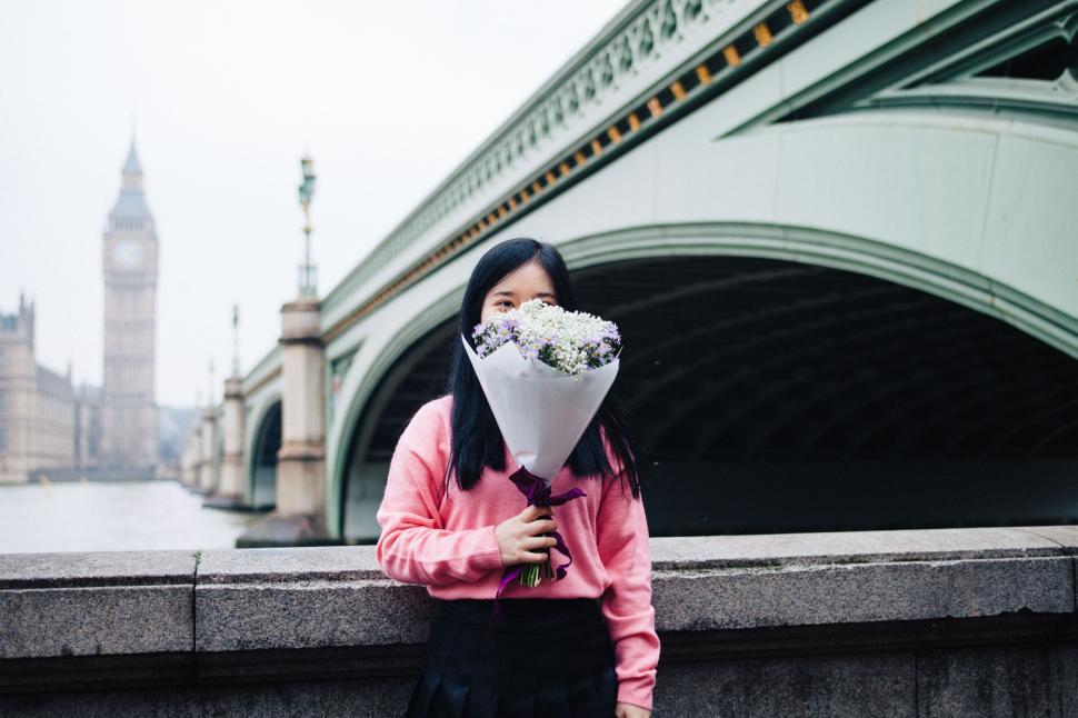 Free Image of Woman Holding Bouquet of Flowers in Front of Bridge 