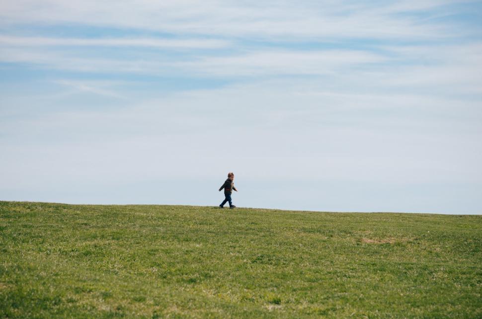 Free Image of Person Walking Across Lush Green Field 