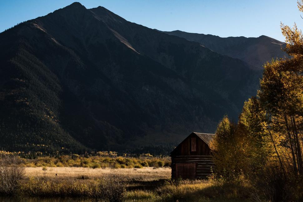 Free Image of Cabin Amidst Field With Mountain Backdrop 