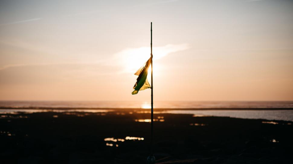 Free Image of Sun Setting Behind Flag on Pole 