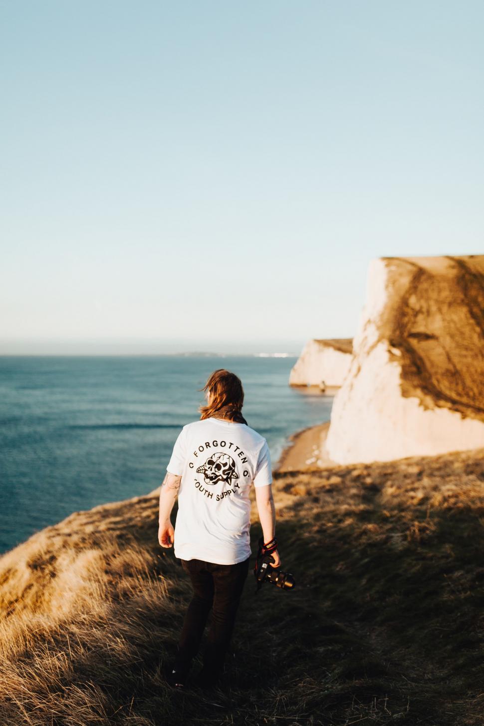 Free Image of Man Walking Up a Hill Towards the Ocean 