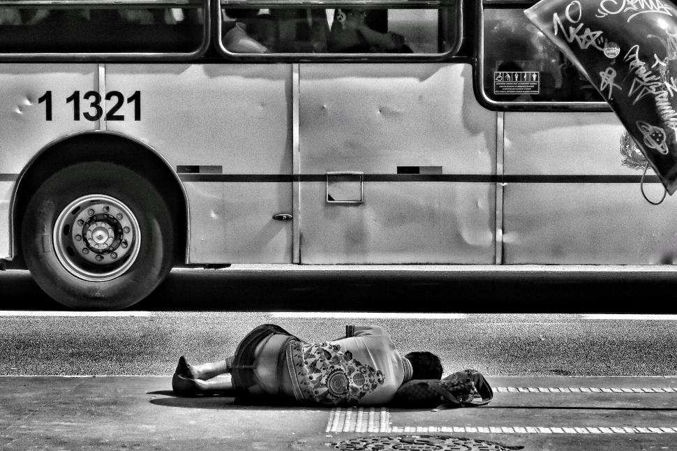 Free Image of Person Laying on Ground in Front of Bus 